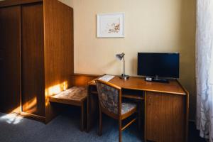 a room with a desk with a television and a chair at Pension Heinrich Heine in Lutherstadt Wittenberg