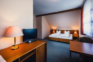 een hotelkamer met een bed en een bureau met een televisie bij Pension Heinrich Heine in Lutherstadt Wittenberg
