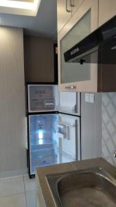 a kitchen with an empty refrigerator and a stove at Apt m34 square by kiiw in Bandung