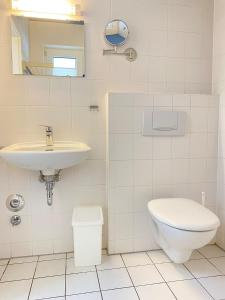 a white bathroom with a sink and a toilet at Haus Claudia in Zingst