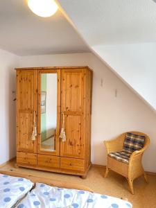 a bedroom with a wooden cabinet and a chair at Haus Claudia in Zingst
