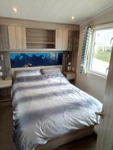 a bedroom with a large bed with a blue headboard at Spacious Comfortable Surf Shack Caravan 35 x 12ft with Sea View Haven Littlesea Weymouth in Weymouth