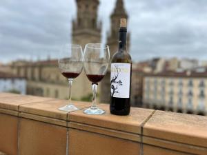 a bottle of wine and two wine glasses on a ledge at ATICO Catedral Barbacoa y Aire sin ascensor By Apartamentos Logrono in Logroño