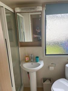 a bathroom with a sink and a shower and a mirror at Swift Holiday Caravan Rockley Park in Lytchett Minster