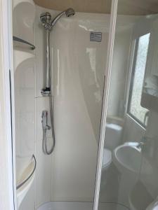 a white bathroom with a shower and a toilet at Swift Holiday Caravan Rockley Park in Lytchett Minster