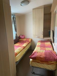 two twin beds in a small room with a cabinet at Swift Holiday Caravan Rockley Park in Lytchett Minster