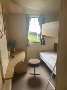 a small room with a bed and a chair and a desk at Swift Holiday Caravan Rockley Park in Lytchett Minster