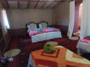 マハミドにあるBivouac Sahara Passionsのベッド2台、テーブル、椅子2脚が備わる客室です。