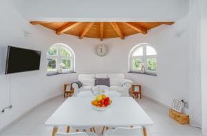 Villa Aria private Pool near Vrsar في فيرسار: غرفة معيشة بيضاء مع طاولة بيضاء مع وعاء من الفواكه
