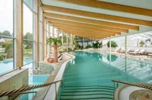 an indoor pool in a building with glass walls at Hotel Deimann in Schmallenberg