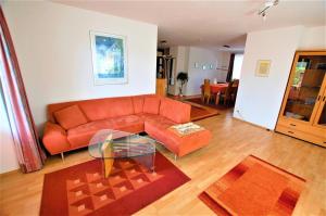 sala de estar con sofá naranja y mesa de cristal en Gästehaus Jäger Ferienwohnungen, en Gersfeld