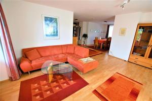a living room with an orange couch and a glass table at Gästehaus Jäger Ferienwohnungen in Gersfeld