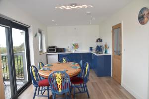 eine Küche mit einem Tisch und Stühlen sowie eine Küche mit blauen Schränken in der Unterkunft The Haven a quiet countryside retreat in Bude