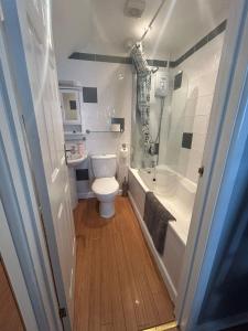 a bathroom with a toilet and a tub and a sink at Turnstone in Seaton