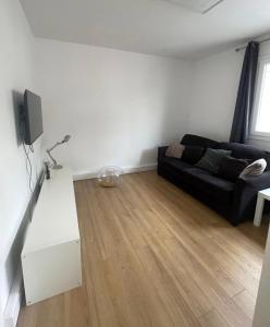sala de estar con sofá negro y suelo de madera en BizFinding Paris, en Montrouge