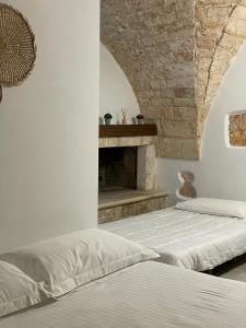 two beds in a bedroom with a stone fireplace at Longo Stone House in Castellana Grotte