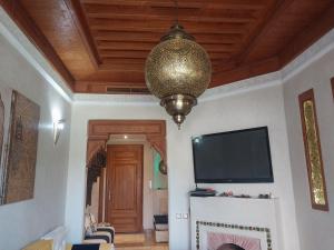 马拉喀什marrakech palmeraie village Etablissement jasmin的客厅配有吊灯和电视。