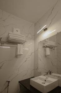 bagno bianco con lavandino e specchio di Arjun - A boutique hotel a Haridwār