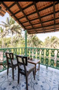 a patio with two chairs and a table on a balcony at Villa Agastya in Betalbatim