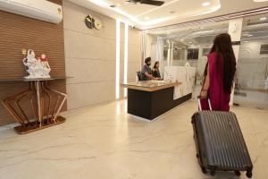 Arjun - A boutique hotel في حاريدوار: امرأة بحقيبة سفر تقف في بهو الفندق