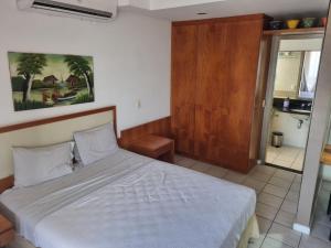 1 dormitorio con 1 cama blanca y armario de madera en Flat Casa del Mar Barra da Tijuca, en Río de Janeiro