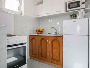uma cozinha com um lavatório e um frigorífico branco em Maki Apartments - Plavi Horizonti Beach em Tivat