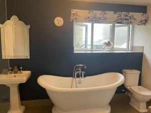 a bathroom with a tub and a toilet and a window at The Coach House & The Stables Holiday Homes Windy Bank Hall Green Moor Yorkshire Peak District in Wortley