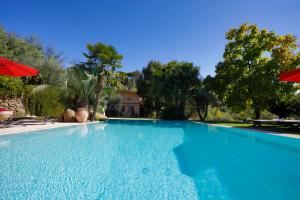 a large blue swimming pool with umbrellas and trees at Pozzo Antico in Morlupo