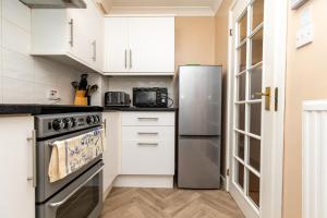 a kitchen with white cabinets and a stainless steel refrigerator at Comfortable and Spacious Superb Holiday Home in Llanelli, Dog Friendly in Llanelli