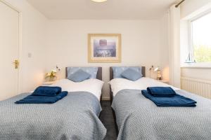 Dos camas en una habitación con almohadas azules. en Comfortable and Spacious Superb Holiday Home in Llanelli, Dog Friendly, en Llanelli
