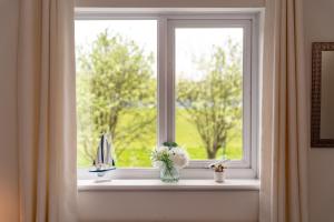 a window with a vase of flowers on a window sill at Comfortable and Spacious Superb Holiday Home in Llanelli, Dog Friendly in Llanelli