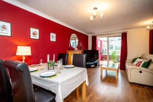 a dining room with a table and a red wall at Comfortable and Spacious Superb Holiday Home in Llanelli, Dog Friendly in Llanelli
