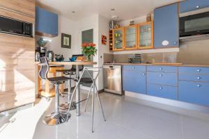 a kitchen with blue cabinets and a table with stools at Le Chalet des Fanières in Chartres