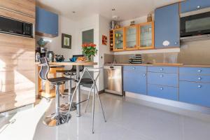a kitchen with blue cabinets and a table with stools at Le Chalet des Fanières in Chartres