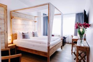 1 dormitorio con cama con dosel y mesa con flores en Eyja Guldsmeden Hotel, en Reikiavik