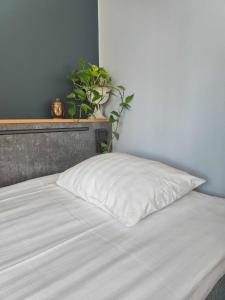 un cuscino bianco seduto su un letto con una pianta di Hotel Linnasmäki a Turku