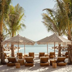a beach with chairs and umbrellas and the ocean at Splendor 1BR with Breathtaking Palm Views in Dubai