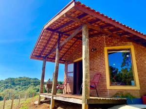 Una casa de ladrillo con una gran ventana y dos sillas en un porche. en Chalé Pedra Chanfrada 02, en Gonçalves 2 fotos más
