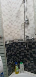 a bathroom with a shower with black and white tiles at City Center Apartment in Shkodër