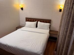 Schlafzimmer mit einem Bett mit weißer Bettwäsche und Kissen in der Unterkunft The Lake Palm Hotel in Kalkutta