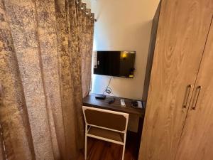 Zimmer mit einem Schreibtisch, einem TV und einem Stuhl in der Unterkunft The Lake Palm Hotel in Kalkutta