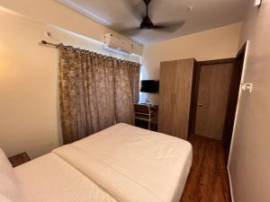 Schlafzimmer mit einem Bett und einem Deckenventilator in der Unterkunft The Lake Palm Hotel in Kalkutta