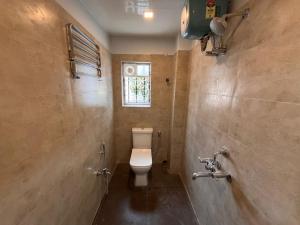 uma casa de banho com um WC e uma janela em The Lake Palm Hotel em Calcutá