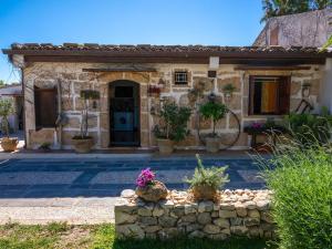 a stone house with a stone fence in front of it at La Virgy per Noto with share swimming pool with woderful seaview in Avola