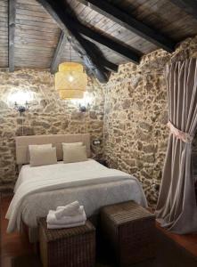 FerreiraにあるCasa con Piscina *Ribeira Sacra*のベッドと石の壁のある寝室