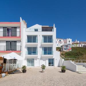 ein weißes Gebäude am Strand mit Pflanzen davor in der Unterkunft Residence Sol e Mar in Salema