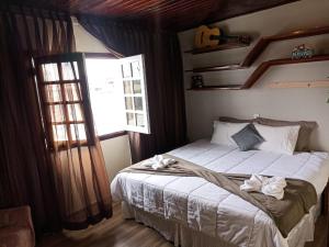 um quarto com uma cama com lençóis brancos e uma janela em Vilarejo da Esperanza em Campos do Jordão