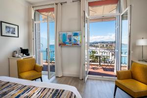a bedroom with a bed and two chairs and a balcony at Hotel Suisse in Nice