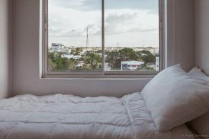 Bett in einem Zimmer mit einem großen Fenster in der Unterkunft hei apartment in Bacolod City