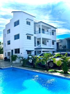 a white building with a car parked in front of a swimming pool at Sosua Sweet Vacations in Sosúa